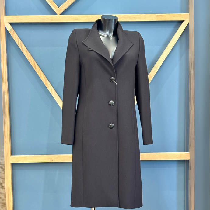 Black coat on a mannequin against a blue wall with geometric wooden frame