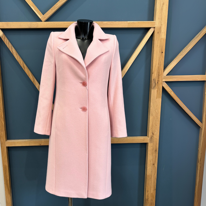 Pink coat on a mannequin against a blue wall with wooden geometric patterns