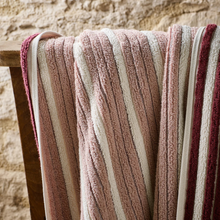Load image into Gallery viewer, Striped towel with pink, beige, and red colors draped over a wooden surface against a stone wall background.
