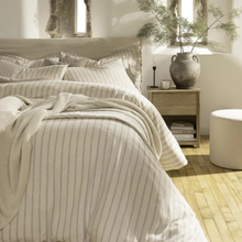 Load image into Gallery viewer, Neatly made bed with striped bedding in a bright bedroom.
