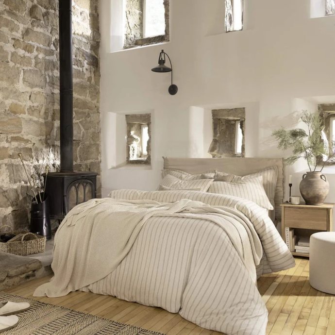 Cozy bedroom with stone wall, bed, and wooden floor.