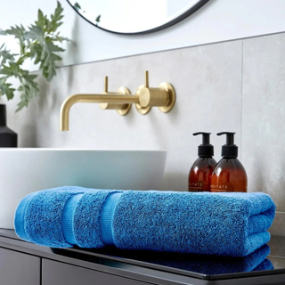 Bathroom setting with blue towels, gold faucet, and bottles on a counter.