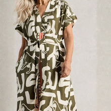 Load image into Gallery viewer, Woman wearing a green and white patterned dress against a plain background
