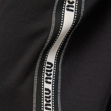 Load image into Gallery viewer, Close-up of a black fabric with white and gray trim featuring text.
