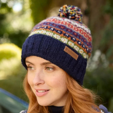 Load image into Gallery viewer, A woman wearing a navy blue knit beanie with a multicolor Fair Isle pattern and a matching pom-pom. The beanie has a brown leather brand patch that reads 'BONSAI'.
