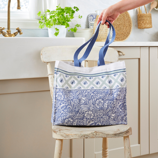 Tote bag with blue and white patterns held by a hand in a kitchen setting.