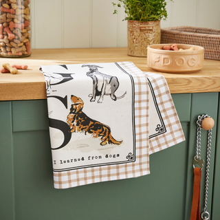 Dog-themed kitchen towel hanging on a cabinet with pet accessories in the background.