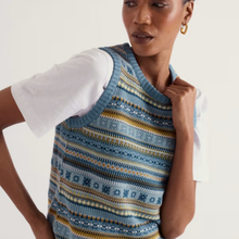 Load image into Gallery viewer, A woman wearing a blue and yellow patterned knit sweater vest over a white t-shirt, photographed against a clean off-white studio background.
