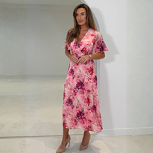 Load image into Gallery viewer, Woman wearing a pink floral dress in a minimal indoor setting
