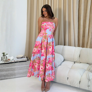Woman in a floral strapless dress standing in a living room.