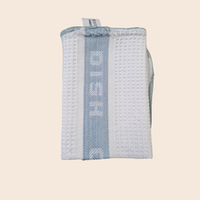 Load image into Gallery viewer, Folded blue and white textured fabric with DishCloth branding on a beige background
