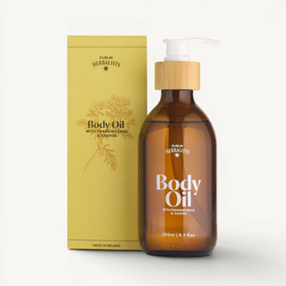 Brown bottle of body oil with a wooden pump and yellow packaging on a white background