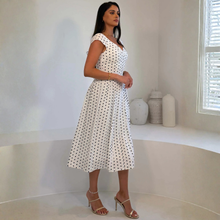 Load image into Gallery viewer, Woman wearing a white dress with black polka dots in a minimalistic room.

