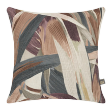 Load image into Gallery viewer, A square decorative throw pillow featuring an abstract botanical pattern with overlapping leaf-like strokes in beige, brown, muted purple, and charcoal gray on a cream background. A small black fabric tag on the lower right edge reads 'THE BOX'.
