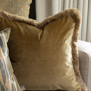 Brown velvet pillow with fringes on a sofa