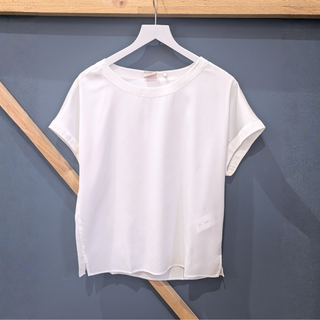 White t-shirt on a hanger against a dark blue wall with wooden accents