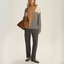 Load image into Gallery viewer, Person wearing a color-blocked sweater and holding a brown bag on a plain background

