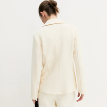 Load image into Gallery viewer, A woman shown from the back wearing a structured cream-colored blazer and matching trousers against a plain white studio background.
