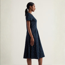 Load image into Gallery viewer, Woman wearing a navy dress with star pattern on a plain background
