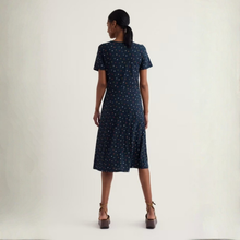 Load image into Gallery viewer, Woman wearing a navy dress with white polka dots on a plain background
