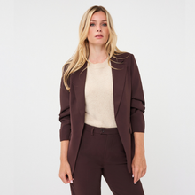 Load image into Gallery viewer, A blonde woman modeling a dark brown tailored blazer, matching trousers, and a cream knit top against a plain light gray studio background.
