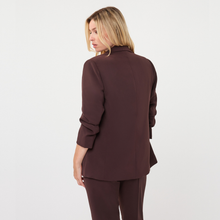 Load image into Gallery viewer, A woman shown from the back wearing a dark brown tailored blazer and matching trousers against a plain light gray studio background.

