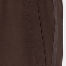 Load image into Gallery viewer, Close-up of a dark brown garment showing a side seam, a vertical welt pocket, and a contrasting textured inner lining.

