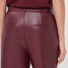 Load image into Gallery viewer, Close-up back view of a person wearing high-waisted burgundy faux-leather trousers with a matching belt and two rear welt pockets.
