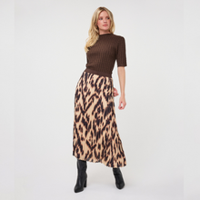 Load image into Gallery viewer, A woman modeling a brown ribbed short-sleeve mock neck top paired with a beige and brown leopard print midi skirt and black ankle boots, shot against a plain white studio background.
