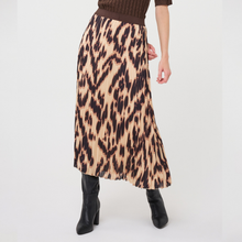 Load image into Gallery viewer, A model wearing a pleated midi skirt with a brown and beige leopard print pattern, paired with a brown knit top and black ankle boots, shown from the waist down on a light gray studio background.
