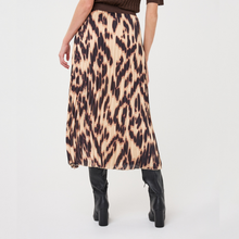 Load image into Gallery viewer, A model from the back wearing a pleated midi skirt with a brown and beige leopard print, paired with black knee-high boots against a plain white studio background.
