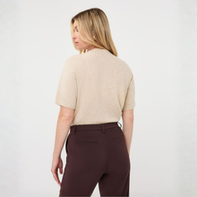 Load image into Gallery viewer, A woman shown from the back wearing a short-sleeve knit top in a light oatmeal beige color and dark brown trousers, against a plain white studio background.
