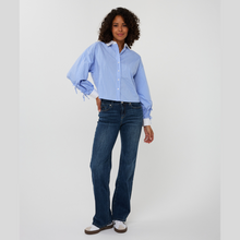 Load image into Gallery viewer, Woman wearing a light blue button-up shirt and dark blue jeans on a white background
