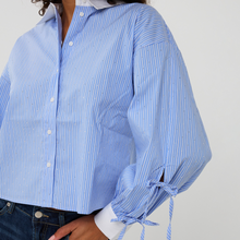 Load image into Gallery viewer, Blue striped shirt with tied sleeves on a plain background
