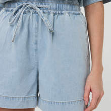 Load image into Gallery viewer, Light blue denim shorts worn by a person on a plain background
