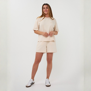 Woman wearing a beige outfit with shorts and a top on a white background