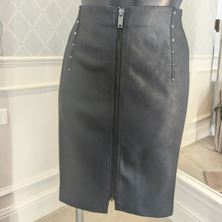 Front view of Eva Kayan Faux leather Skirt Front Zip, with a wallpapered background.