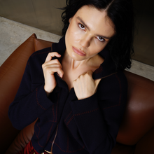 Load image into Gallery viewer, Woman sitting on a brown leather chair wearing a dark jacket.
