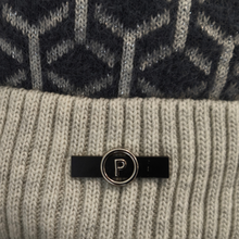 Load image into Gallery viewer, Detailed view of a thick, cosy beanie hat with a striking black and white geometric design, complemented by a stylish black and silver “P” logo.
