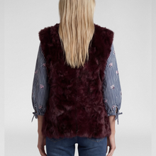 Load image into Gallery viewer, A woman viewed from the back wearing a deep burgundy faux fur vest over a blue and white striped long-sleeve blouse with embroidered details and blue jeans, against a light gray studio background.
