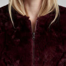 Load image into Gallery viewer, Close-up of a person wearing a plush faux-fur zip jacket in deep burgundy, showing the collar, zipper, and hair against a light neutral background.
