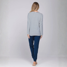 Load image into Gallery viewer, A woman is shown from behind wearing a long-sleeve top with thin navy and white horizontal stripes and dark navy pants, standing against a light gray studio background.
