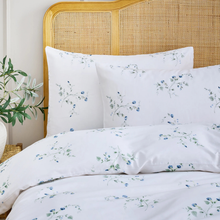 Load image into Gallery viewer, Floral-patterned bedding set on a bed with a wicker headboard.

