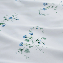 Load image into Gallery viewer, White fabric with a delicate watercolor-style floral print featuring blue flowers and green leaves.
