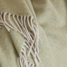 Load image into Gallery viewer, Close-up of a woven textile with a pale sage green and cream herringbone pattern and white fringe.
