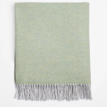 Load image into Gallery viewer, A folded woven throw blanket with a pale sage green and light gray herringbone pattern and fringed edges, shown against a plain white background.
