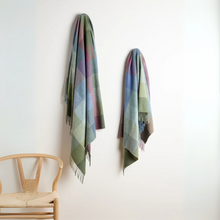 Load image into Gallery viewer, Two plaid scarves hanging on a white wall with a wooden chair below.
