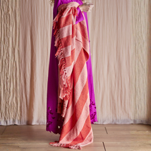 Load image into Gallery viewer, Person holding a vibrant pink and red striped throw with tassels against a neutral background
