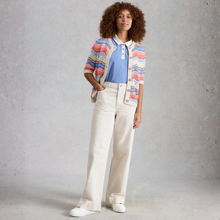 Load image into Gallery viewer, Woman wearing a colorful cardigan, blue shirt, and white pants against a gray background
