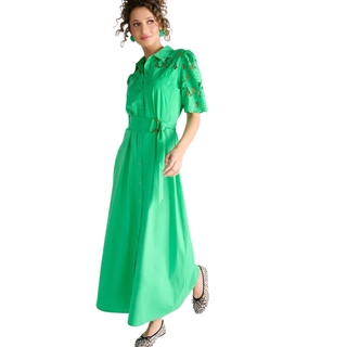 Woman wearing a green dress with floral embroidery on a white background